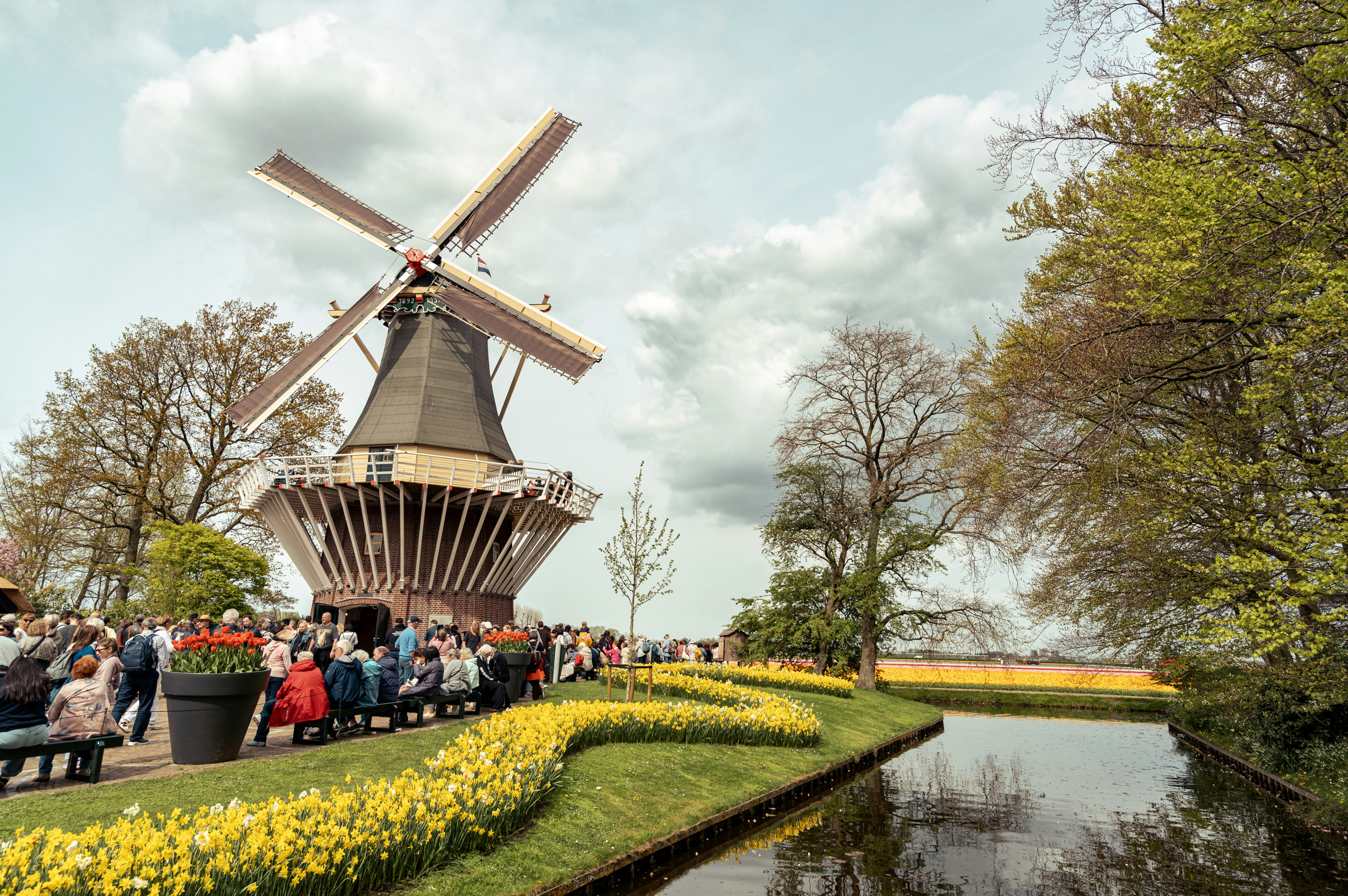 Traditional windmill with blooming yellow tulips and canal